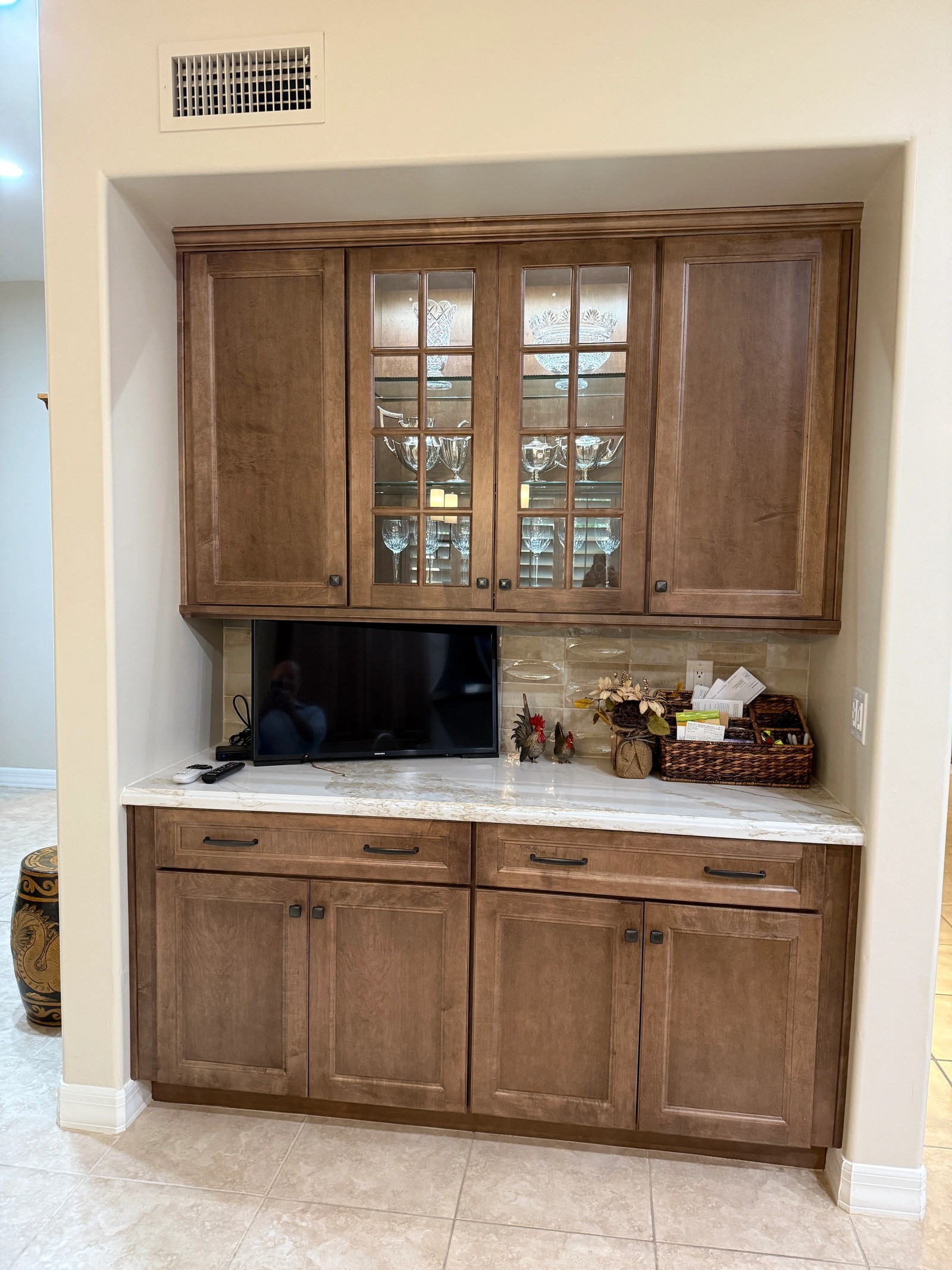Butler pantry with glass-front upper cabinets, stained wood doors and a marble counter
