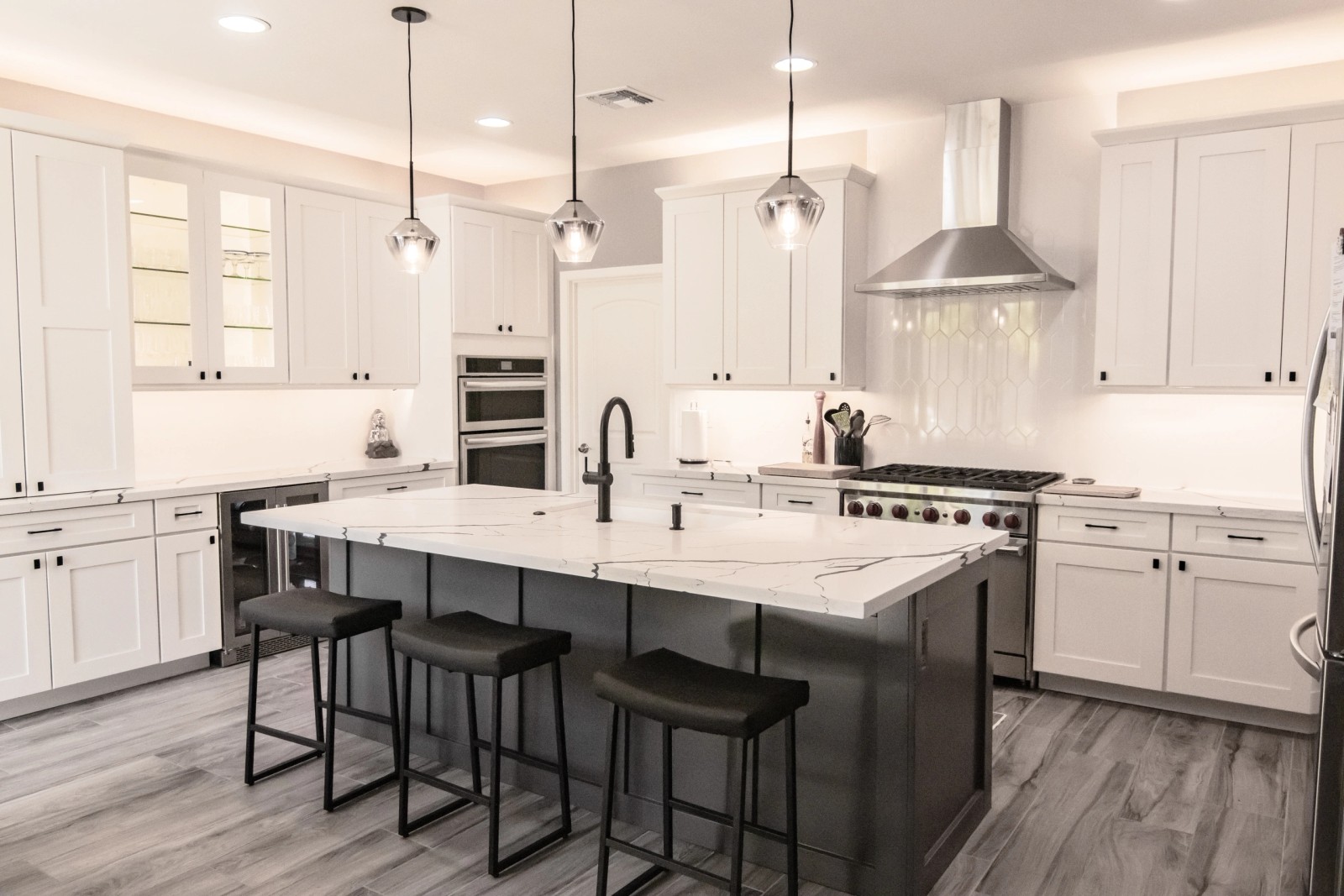 White kitchen with a charcoal island, quartz top and bar stools