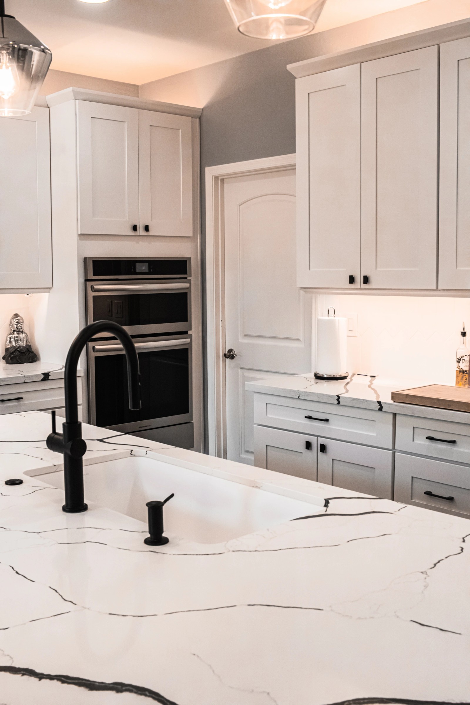 White shaker kitchen with a veined quartz island and matt black fittings